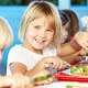 Elementary Kids Enjoying Healthy Lunch In Cafeteria