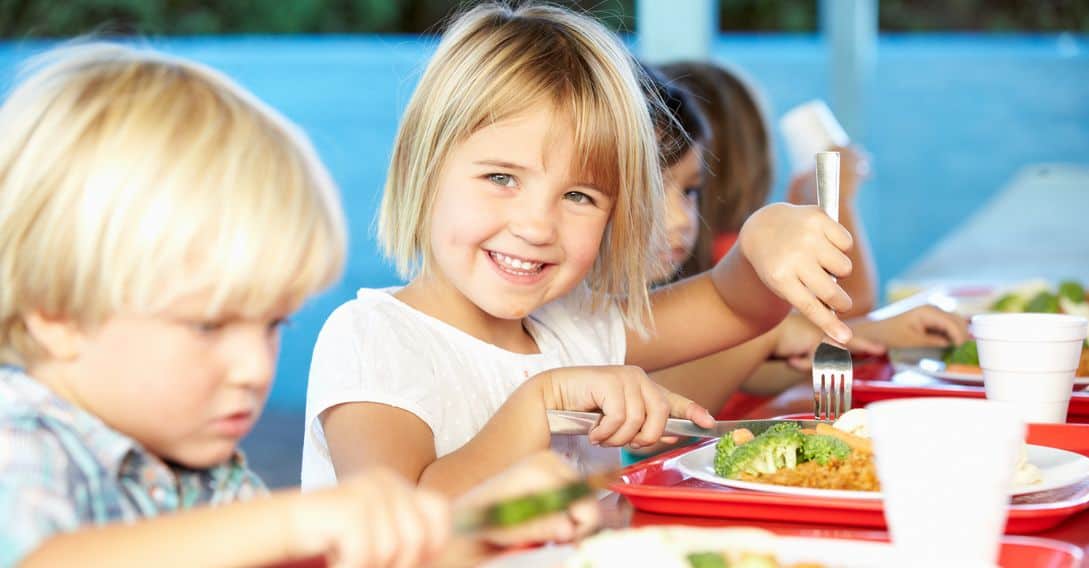 Elementary Kids Enjoying Healthy Lunch In Cafeteria